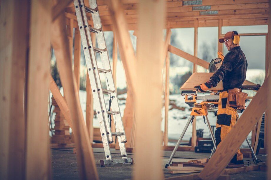 Contractor cutting lumber with a miter saw at a framed job site
