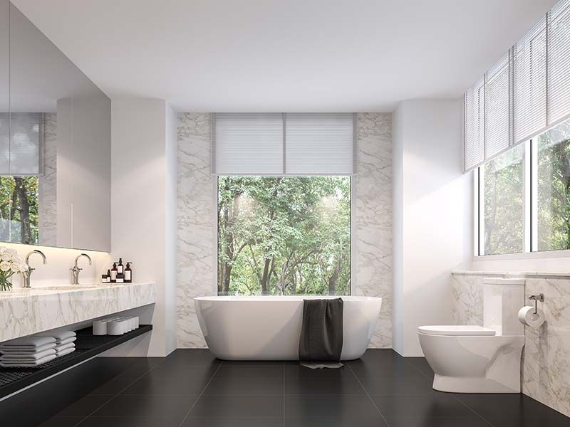 Remodeled bathroom with freestanding soaking tub and marble tile
